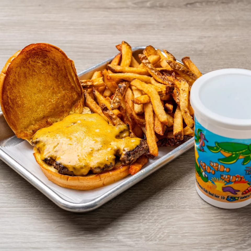 Dempsey Burger Bar cheeseburger with fries and a drink on a metal tray.